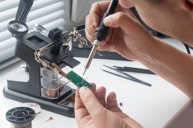 Bir lehim istasyonu ve diğer bileşenler kullanılarak lehimleme ile radyo panosunun onarımı