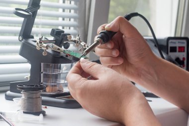 Bir lehim istasyonu ve diğer bileşenler kullanılarak lehimleme ile radyo panosunun onarımı