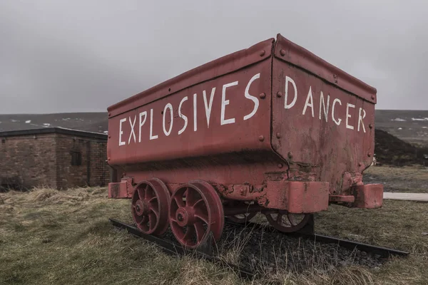 A bright red, weathered, mine cart, used to carry explosives to the Welsh coal mines. The cart is located in the Big Pit, tourist attraction in Ebbw Vale, in the South Wales Valleys