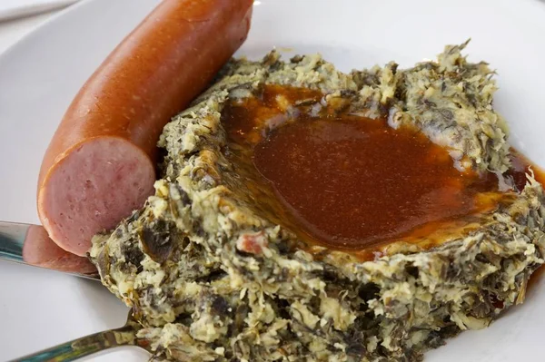 Dutch Boerenkool Stampot (mashed pot of mashed potatoes mixed with kale), smoked sausage and a pool of gravy. Traditional Dutch food dish, considered comfort food.