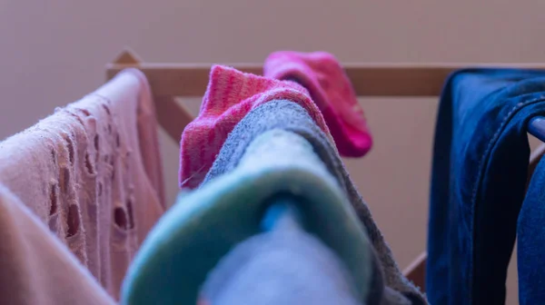 Сосредоточьтесь на розовом носке, высыхающем на вешалке для белья с одеждой другой женщины, и несходные носки размылись на переднем плане. Изображение дня стирки, работы по дому, уборка, несравненные носки, поиск носков и т.д. . — стоковое фото
