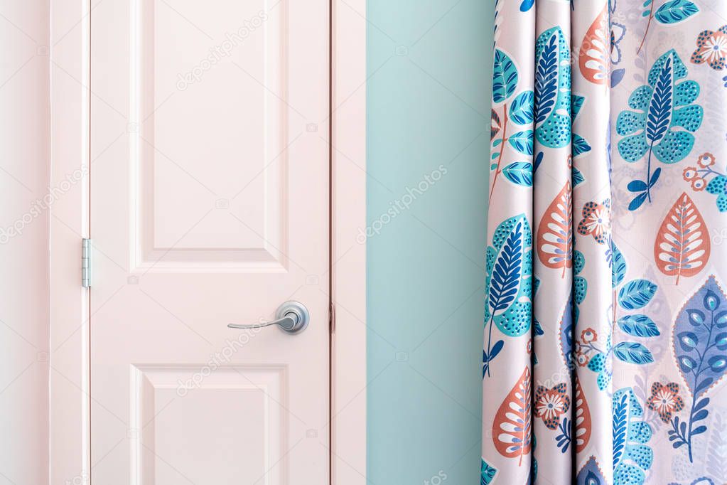Home interior showing colonial closet door with turquoise curtain decor and light blue painted wall.