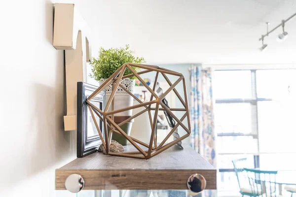 Home wall shelf with decorative knick knacks, including a geometric wire object, a letter 't', picture frames and a planter. Bright living room shelf. — Stock Photo, Image