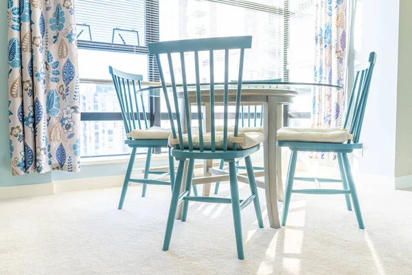 Bright, blue and white colorful dining table and chairs, with blue and white decor and a designed home interior scheme. Sunbeams coming through windows. Clean home. — Stock Photo, Image