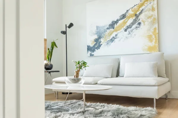 Beyaz mobilya ve modern iç tasarım ile Daire oturma odası açısı görünümü, ve bazı ev bitkileri. Futon kanepe, sehpa, yan masa ve duvar sanatı gösteren.