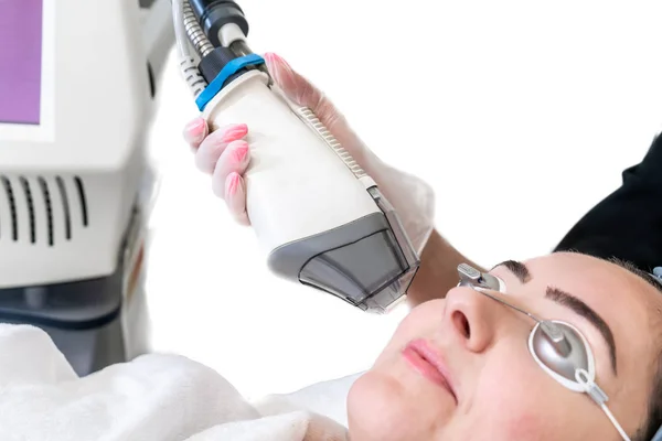 Laser treatment being performed on female patient for face rejuvenation. White background and hand piece showing. Patient wearing eye protection. — Stock Photo, Image