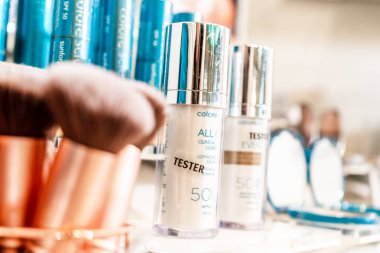 Colorscience test ürünleri, perakende ekranda, parlak bir makyaj tezgahında. Mineral makyaj, dudak rengi ve bronz makyaj fırçaları, seçici odak ile.