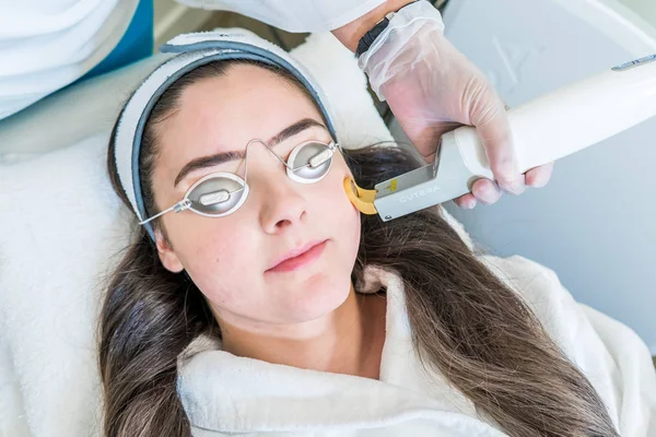 Laser skin treatment using the Excel V laser by Cutera. Cutera logo shows. Patient is wearing laser light protective goggles. Laser handpiece shown in image. — Stock Photo, Image