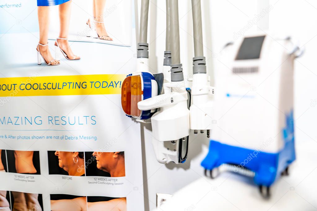 Miniature Coolsculpting machine model in a medspa clinic, on a patient bed in a branded room for cryolipolysis treatment to remove fat.