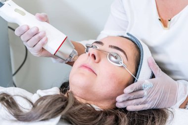 Güzellik kliniğinde cilt sıkılaştırma tedavileri için bir kadının yüzüne radyo frekansı microneedling handpiece uygulayarak Güzellik.