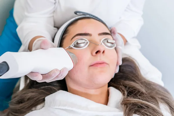 Schoonheidsspecialiste die radiofrequentie in handstuk toepast op het gezicht van een vrouw voor huidverstrakking behandelingen in een Beauty kliniek. — Stockfoto