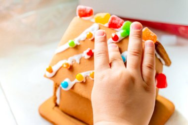 Yaratıcı ve klasik, mevsimlik tatil etkinliği olarak pudra şekeri ile zencefilli evin çatısına şeker topları ve gummies yerleştirerek çocuk parmakları.