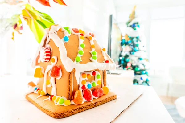 Cute, child-made gingerbread house, with imperfections (a real gingerbread house assembly), for the Christmas holiday season, as a decoration. Classic holiday activity and dessert.