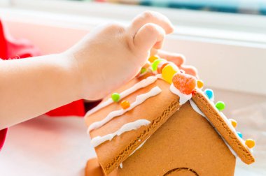 Yaratıcı ve klasik, mevsimlik tatil etkinliği olarak pudra şekeri ile zencefilli evin çatısına şeker topları ve gummies yerleştirerek çocuk parmakları.