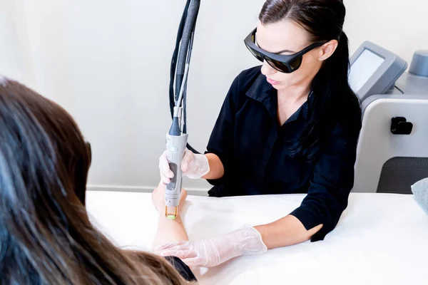 Sessione di depilazione laser con il tecnico di bellezza e paziente femminile, epilazione dei capelli del braccio, in una clinica cosmetologica della pelle . — Foto Stock