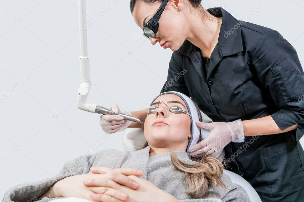 Beauty laser technician performing a cosmetic skin resurfacing session on a female patient, also called a laser peel  or photofacial, with an Er:Yag laser (infrared wavelength).