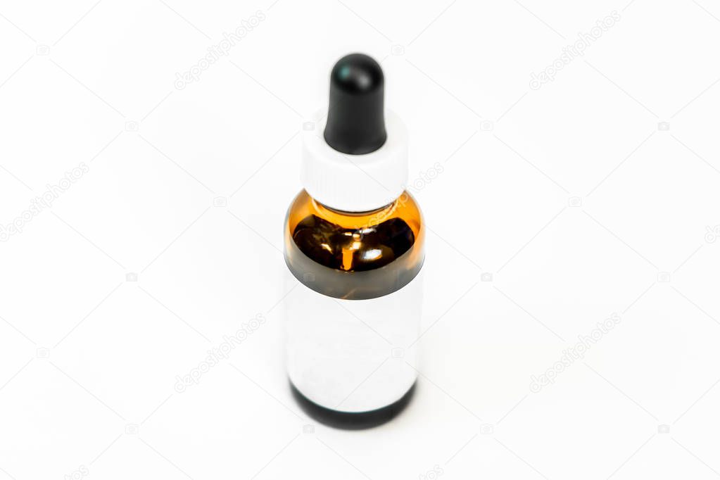 Brown glass eye dropper bottle with lid, and white blank label on a white background, isolated. Room for copy, add your own text. Still life bottle photo.