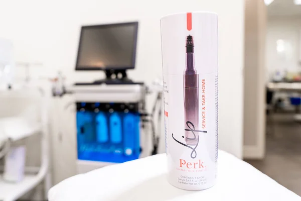 Surrey, BC / Canada - 06/11/19: HydraFacial Perk lip treatment product in package, showing facial treatment machine in the background, in a beauty spa clinic. — Stock Photo, Image