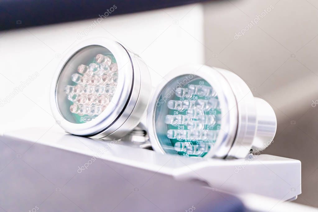 Two LED light therapies for skin, on handles, showing light bulbs. Red LED light for anti-aging and skin smoothing treatment and blue LED light for acne treatments, to kill skin bacteria.