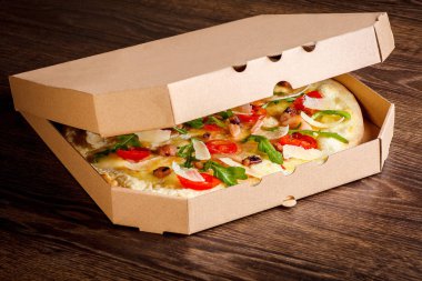 Marka için içinde lezzetli renkli pizza ile temiz üst yüzey açık pizza kutusu. Kahverengi ahşap masada