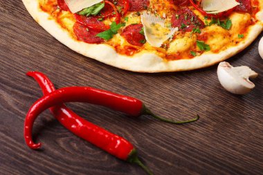 Kahverengi ahşap masada iki kırmızı sıcak Chili biber, pizza ve mantar. Meksikalı, Italyan yemekleri. Üst görünüm. Kapsaisin.