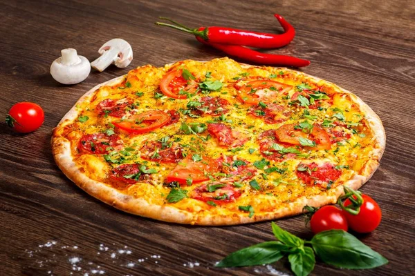 Pizza Italian pepperoni with melted cheese, salami, tomatoes and species on a brown table decorated by mushrooms, red sweet pepper and cherry tomatoes — Stock Photo, Image