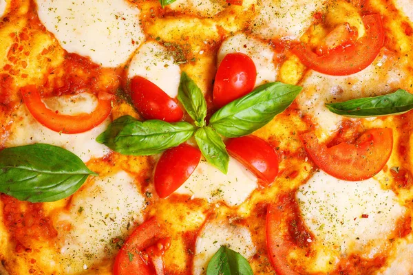 Üst görünüm, erimiş mozzarella peyniri, kırmızı kiraz domates ve taze yeşil fesleğen, mantar, kırmızı tatlı biber ve kiraz ile süslenmiş temiz bir kahverengi masada yaprakları ile Italyan pizza Margherita yakın