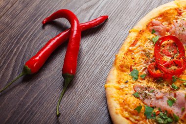 Üst görünüm, taze kırmızı kiraz domates ve taze yeşil fesleğen yaprakları ile süslenmiş kahverengi bir masada jambon, peynir, biber ve otlar ile mantar ve Italyan pizza yakın