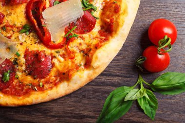 Mantar, kırmızı tatlı biber ve kiraz domates ile süslenmiş kahverengi bir masada parmezan peyniri, domates, salam, pepperoni ve Yeşil fesleğen ile pizza Italyan