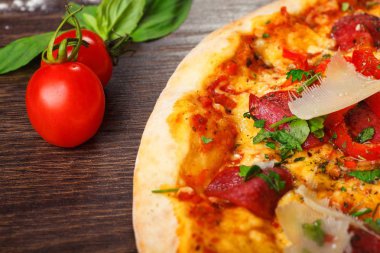 Mantar, kırmızı tatlı biber ve kiraz domates ile süslenmiş kahverengi bir masada parmezan peyniri, domates, salam, pepperoni ve Yeşil fesleğen ile pizza Italyan