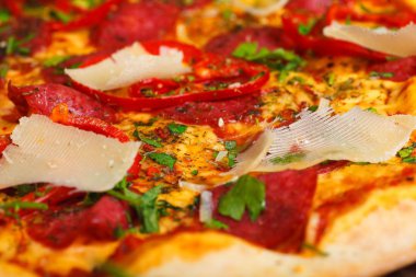 Mantar, kırmızı tatlı biber ve kiraz domates ile süslenmiş kahverengi bir masada parmezan peyniri, domates, salam, pepperoni ve Yeşil fesleğen ile pizza Italyan