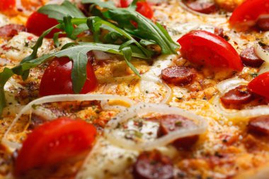 Erimiş mozzarella peyniri, kırmızı kiraz domates, sosis ve taze yeşil kekik kahverengi bir masada kiraz domates tarafından dekore yaprakları ile Italyan pizza yakın