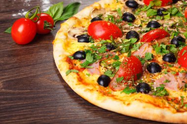 Erimiş peynir, kırmızı kiraz domates, siyah zeytin, jambon ve yeşil yaprakları ile Italyan pizza yakın kadar mantar, kırmızı sıcak biber ve kiraz domates ile süslenmiş kahverengi bir tablo