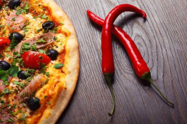 Erimiş peynir, kırmızı kiraz domates, siyah zeytin, jambon ve yeşil yaprakları ile Italyan pizza yakın kadar mantar, kırmızı sıcak biber ve kiraz domates ile süslenmiş kahverengi bir tablo