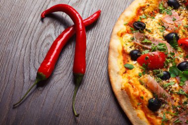 Erimiş peynir, kırmızı kiraz domates, siyah zeytin, jambon ve yeşil yaprakları ile Italyan pizza yakın kadar mantar, kırmızı sıcak biber ve kiraz domates ile süslenmiş kahverengi bir tablo