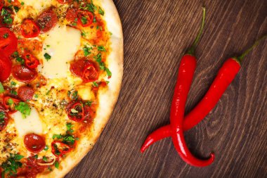 Üst görünüm eritilmiş peynir, sosis, Snack çubukları, biber ve taze yeşil kekik ile Italyan pizza yakın kadar mantar, kırmızı tatlı biber ve kiraz domates ile süslenmiş kahverengi bir masada yaprakları