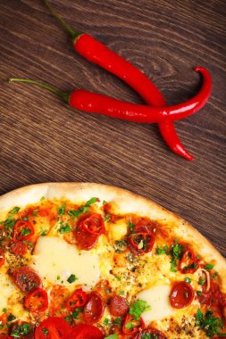 Üst görünüm eritilmiş peynir, sosis, Snack çubukları, biber ve taze yeşil kekik ile Italyan pizza yakın kadar mantar, kırmızı tatlı biber ve kiraz domates ile süslenmiş kahverengi bir masada yaprakları