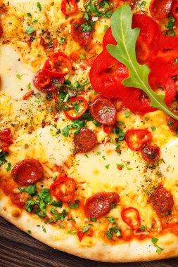 Üst görünüm eritilmiş peynir, sosis, Snack çubukları, biber ve taze yeşil kekik ile Italyan pizza yakın kadar mantar, kırmızı tatlı biber ve kiraz domates ile süslenmiş kahverengi bir masada yaprakları