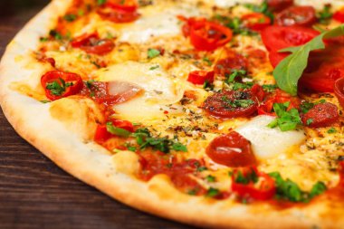 Eritilmiş peynir, sosis, Snack çubukları, biber ve taze yeşil kekik ile Italyan pizza yakın kadar mantar, kırmızı tatlı biber ve kiraz domates ile süslenmiş kahverengi bir masada yaprakları