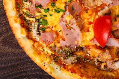 Mantar, kırmızı tatlı biber ve kiraz domates ile süslenmiş kahverengi bir masada erimiş mozzarella peyniri, kırmızı kiraz domates, jambon ve taze yeşil otlar ile üst görünüm Italyan pizza yakın