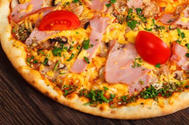 Mantar, kırmızı tatlı biber ve kiraz domates ile süslenmiş kahverengi bir masada erimiş mozzarella peyniri, kırmızı kiraz domates, jambon ve taze yeşil otlar ile üst görünüm Italyan pizza yakın