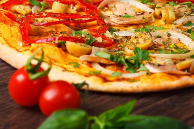 Mantar, kırmızı tatlı biber ve kiraz domates ile süslenmiş kahverengi bir masada eritilmiş peynir, kırmızı domates, biber, mantar, soğan ve otlar ile Italyan pizza yakın