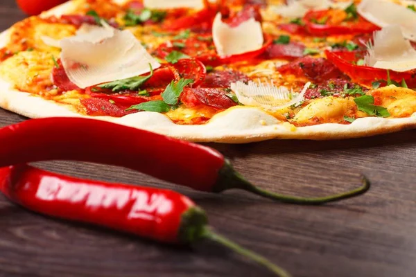 Pizza italiana con queso parmezano, tomates, salami, pepperoni y albahaca verde sobre una mesa marrón decorada con champiñones, pimiento dulce rojo y tomates cherry — Foto de Stock