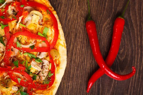 Makarna, kırmızı tatlı biber ve kiraz domates ile süslenmiş kahverengi bir masada eritilmiş peynir, kırmızı domates, biber, mantar, soğan ve otlar ile pizza Italyan