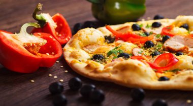 Mantar, siyah zeytin, kırmızı yeşil biber ve roka ile süslenmiş kahverengi bir masada eritilmiş peynir, kırmızı biber, Mısır, soğan, siyah zeytin ve taze bitki baharatlarıyla vejetaryen mantar İtalyan Pizza