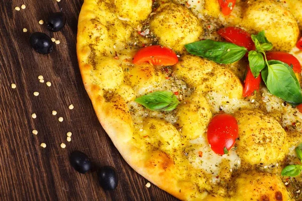 Vista superior de cerca vegetariano italiano margherita pizza queso derretido, tomates rojos cereza y hojas de albahaca verde fresco en una mesa marrón decorada con champiñones, aceitunas negras, pimiento verde rojo y fresco — Foto de Stock