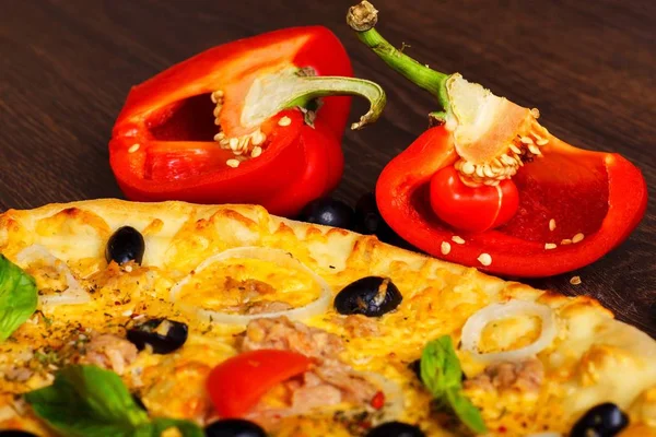 Primer plano de atún vegetariano Pizza italiana queso derretido, aceitunas negras, tomates cherry rojos y hojas de albahaca verde fresca en una mesa marrón decorada con setas, aceitunas negras, pimiento rojo y rúcula fresca — Foto de Stock