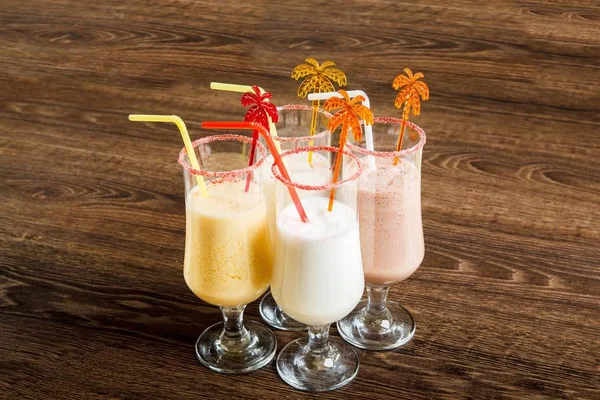 Banana, vanilla and strawberry milk cocktail shake on a on dark wooden table