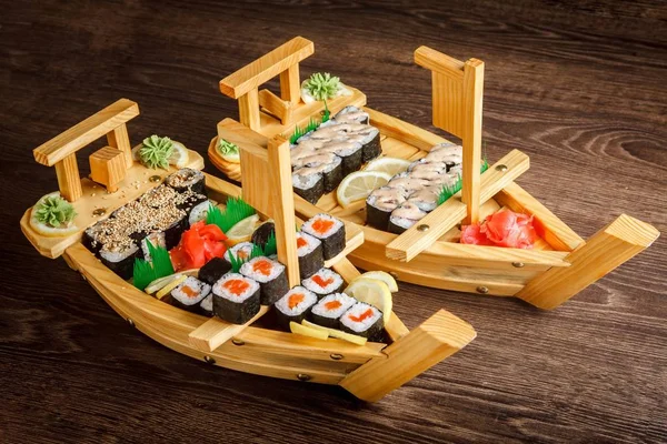 Sushi sashimi szett egy fából készült hajón, barna fából készült asztalon. A dallam, garnéla, garnélarák, gyömbér — Stock Fotó