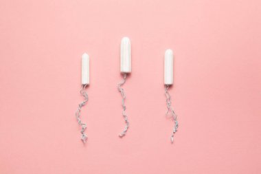 Yumuşak pembe arka planda farklı boyutlarda tamponlar paketlenmeli. Modern kadın samimi jinekolojik hijyen. Eko sıfır atık kavramı. Metin için yer yeri kopyalayın. Düz yatma